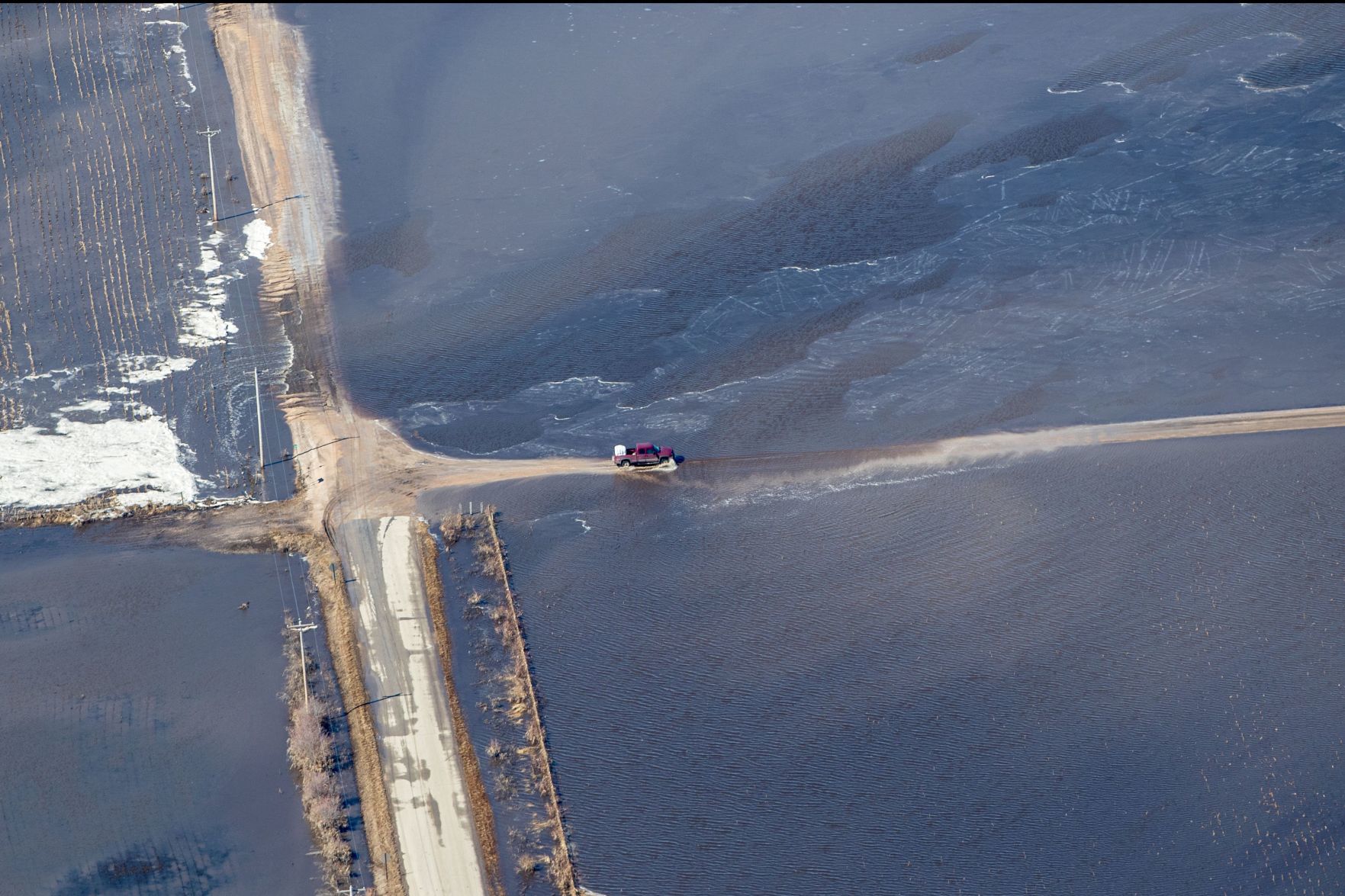A truck drives through a flooded road near the Platte River.